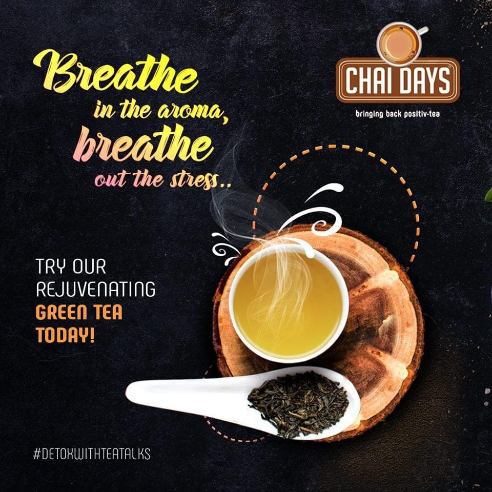Dark chalkboard-style creative with a steaming cup of green tea on a wooden slice and a spoon of leaves, with “Breathe in the aroma, breathe out the stress… Try our rejuvenating green tea today!” and #DetoxWithTeaTalks